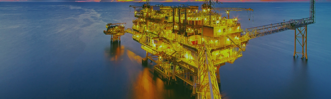 oil production platform lit up at night in a calm sea